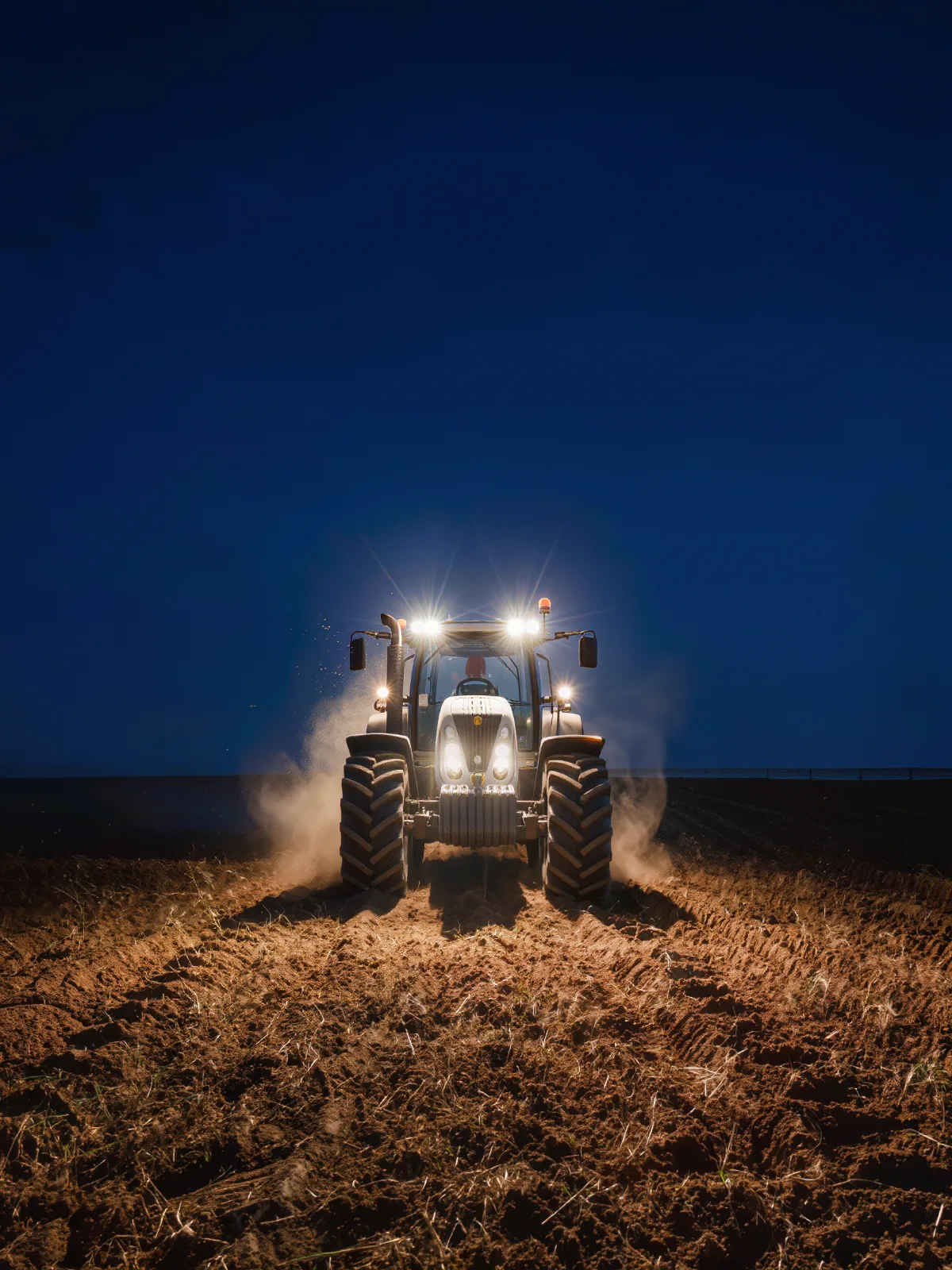 Tractor working a field at night with work lights on