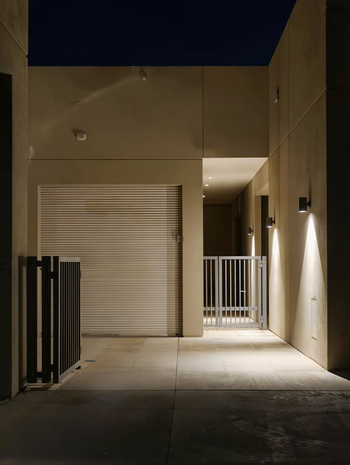 Restricted service area with secured gates behind a resort at night