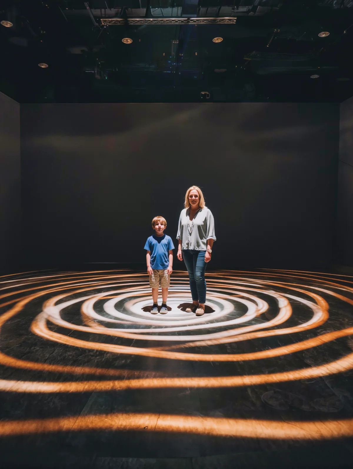 Immersive projection room with light rippling around two visitors