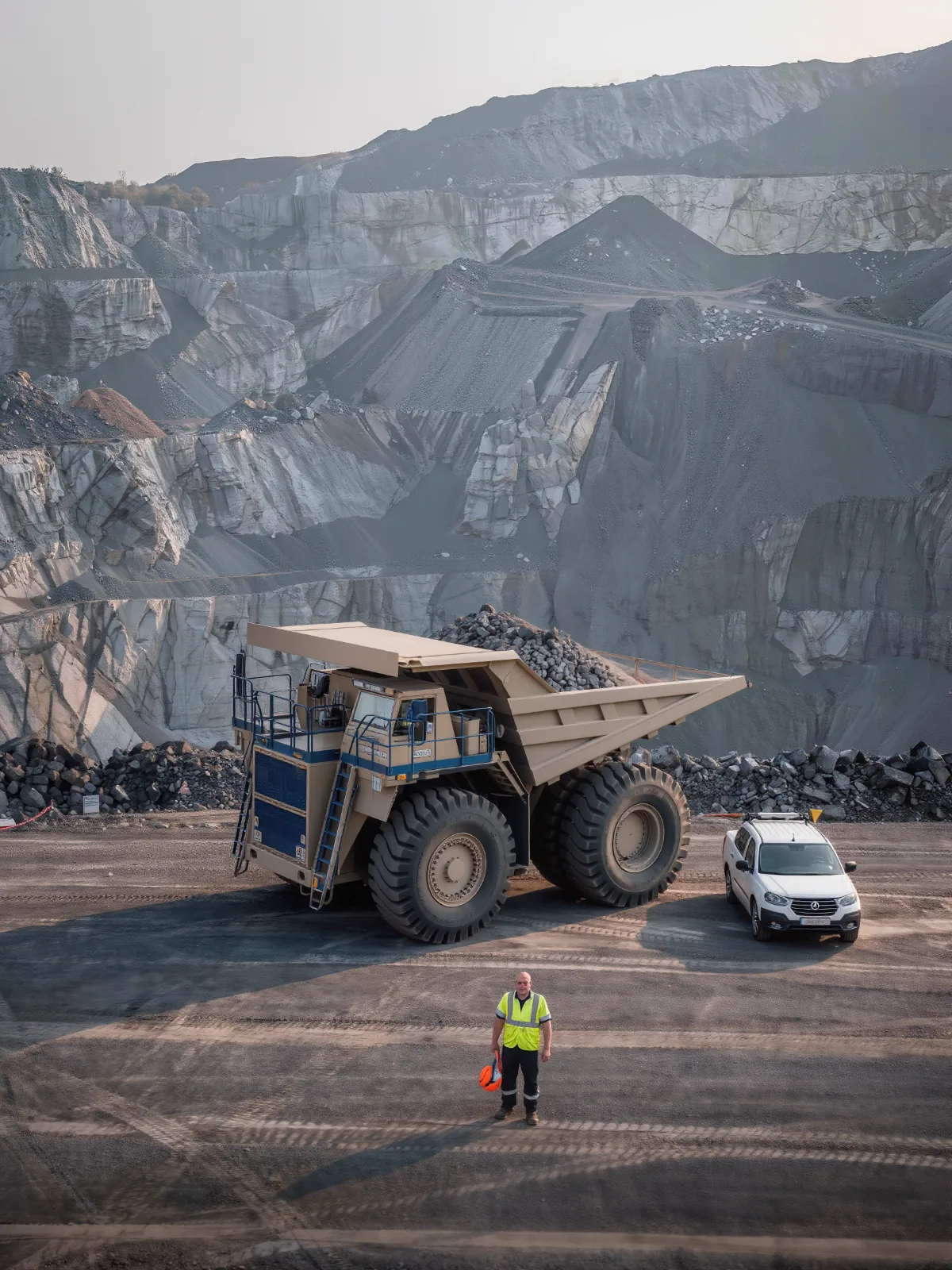 Mining haul truck parked near a light vehicle with a worker standing at a safe distance
