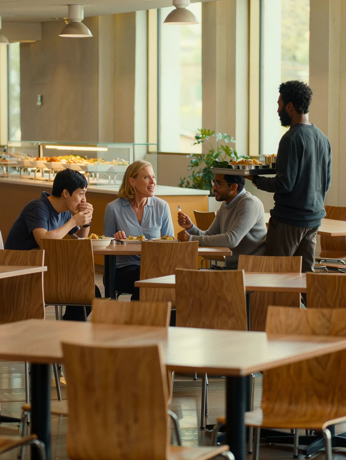 Employees eating and talking at tables in a bright corporate cafeteria