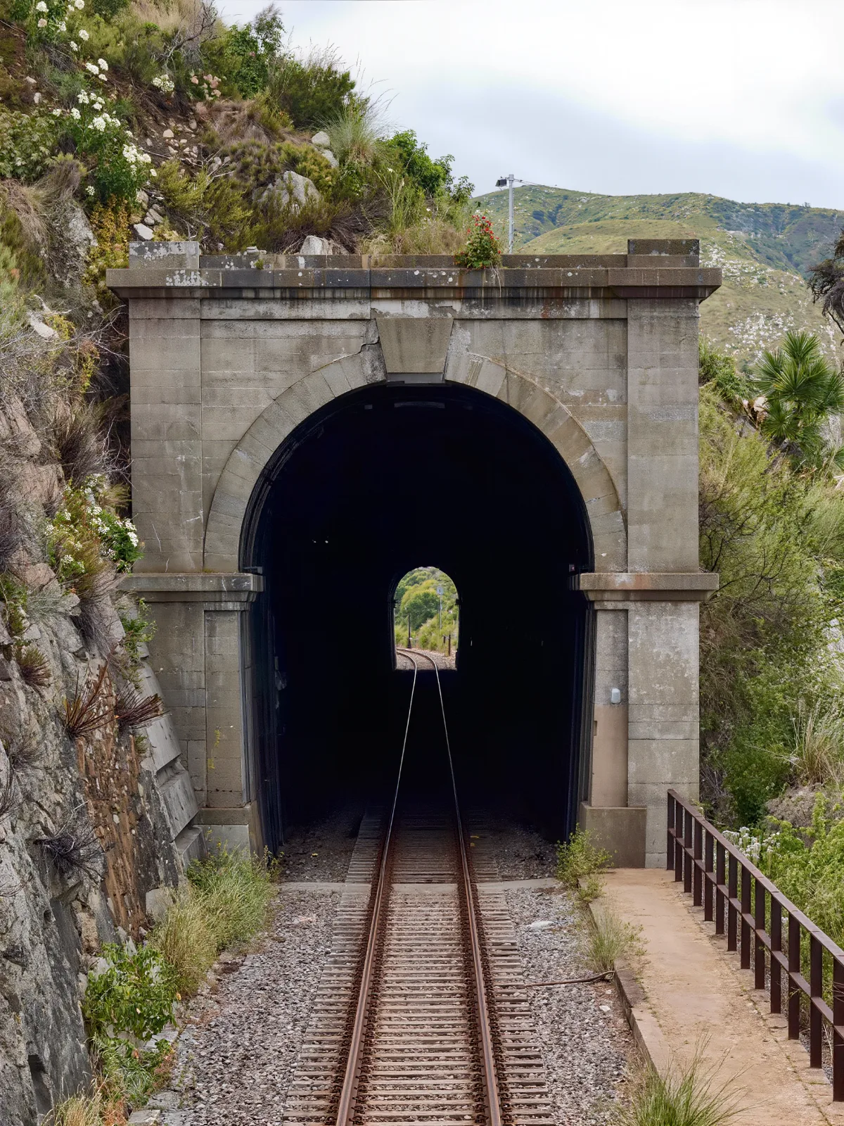 Stone railway tunnel portal with a track entering the hillside
